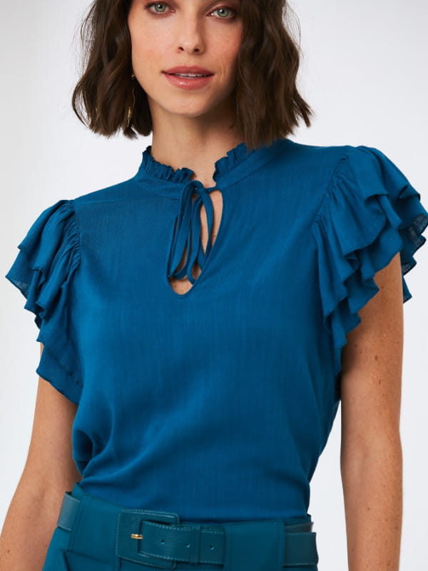 Blusa feminina de crepe: Modelo vestindo uma blusa de crepe viscose com babado azul e amarração na gola.