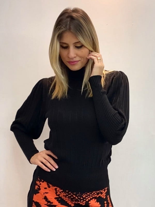 Tecidos para o Inverno 2020: modelo vestindo uma blusa de tricot preta.