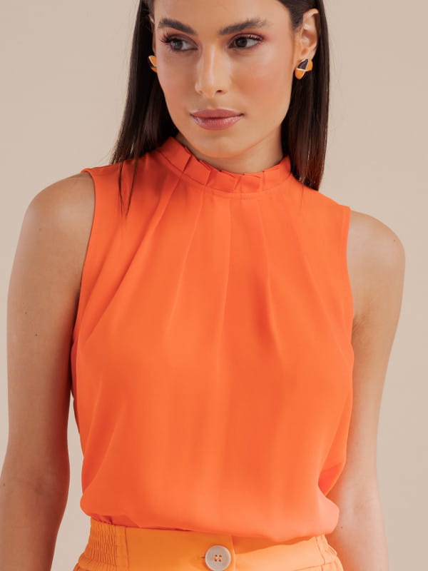Blusa social feminina de crepe: modelo vestindo uma blusa de crepe básica com pregas laranja.