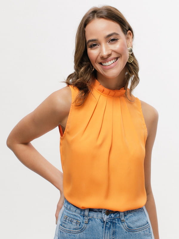 Blusas femininas para trabalhar: modelo vestindo uma blusa de crepe básica com pregas laranja.