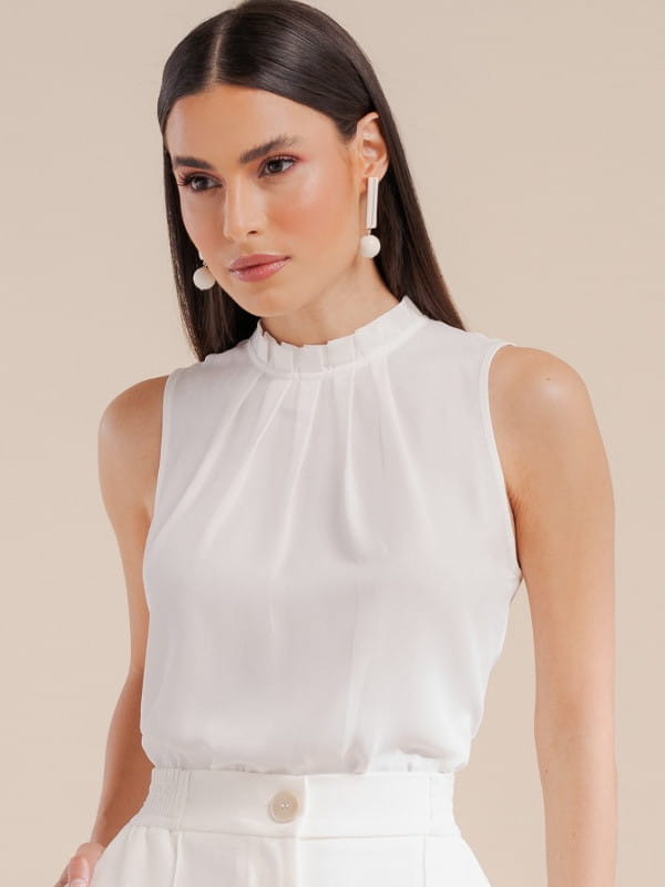 Blusas femininas para trabalhar: modelo vestindo uma blusa de crepe básica com pregas off white.