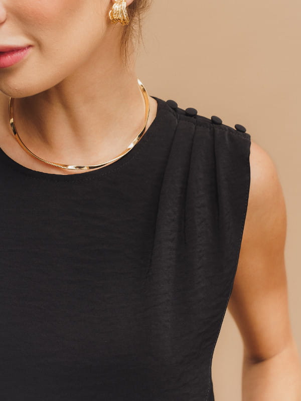 Blusa alfaiataria feminina: modelo vestindo uma blusa regata alfaiataria com botão no ombro preta - detalhes.