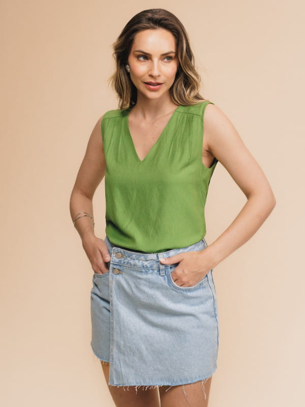 Blusa de viscose lisa feminina: modelo vestindo uma regata com decote V na cor verde com uma calça jeans.