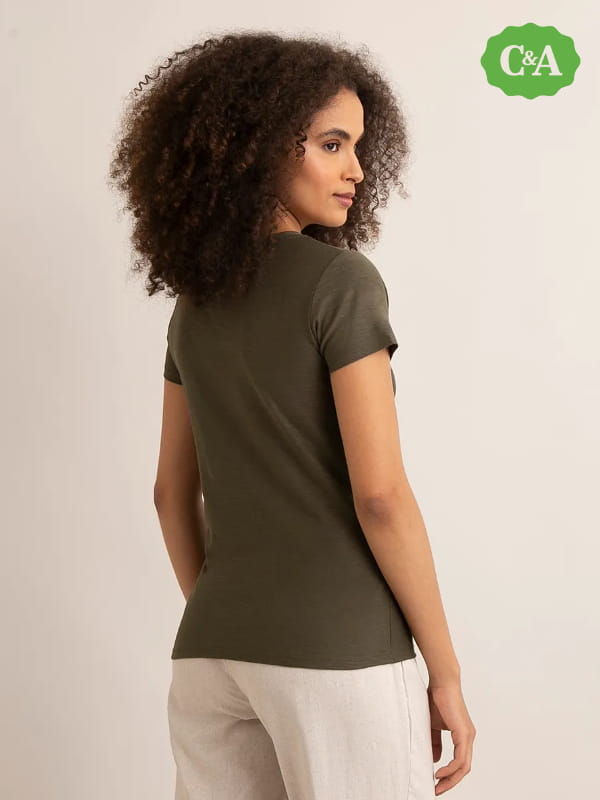 Blusas femininas para uniforme: modelo vestindo uma blusa básica flamê manga curta decote V verde militar - costas.