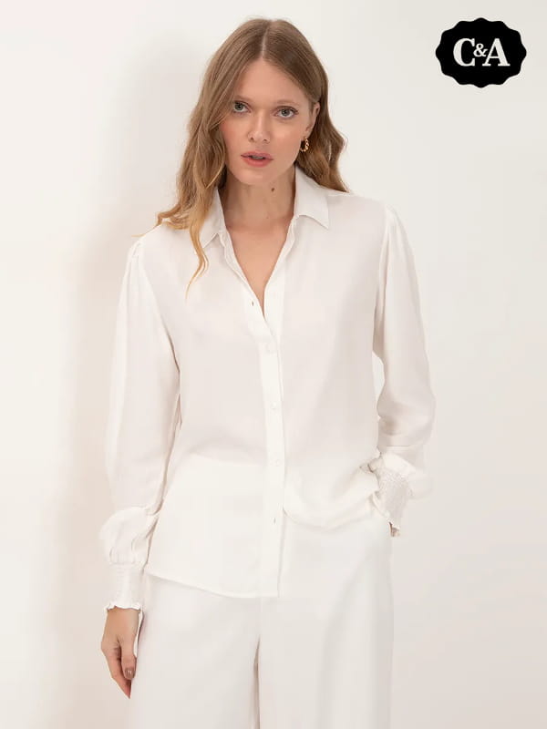 Blusa social feminina: modelo vestindo uma camisa de viscose manga longa bufante off white.