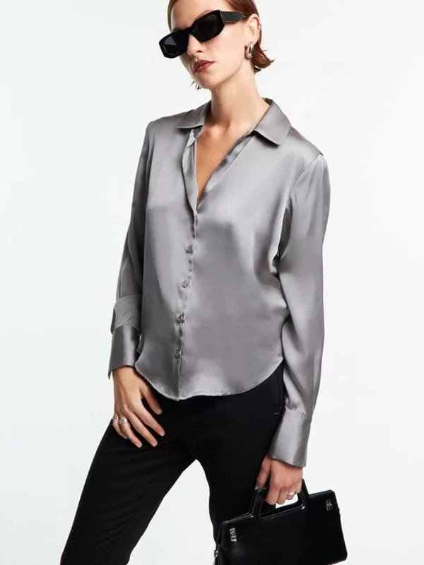 Blusa social feminina: modelo vestindo uma camisa em cetim com recortes e caimento leve prata.