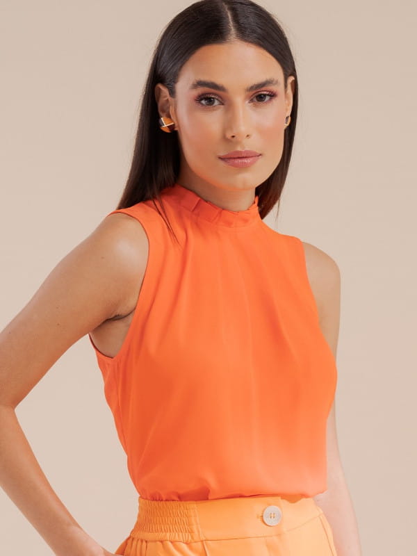 Blusas femininas 2022: modelo vestindo uma blusa regata de crepe básica com pregas laranja.
