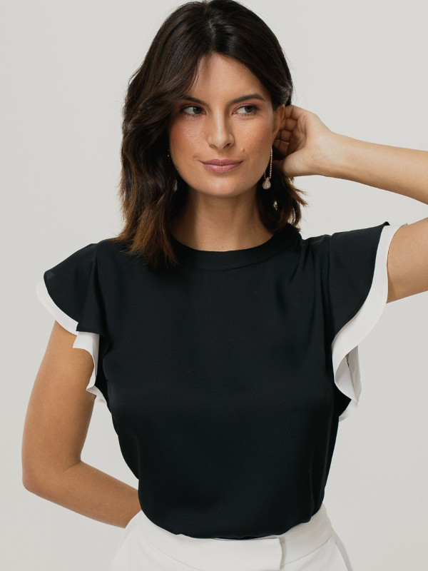 Blusas femininas 2022: modelo vestindo uma blusa preta com detalhe bicolor na manga.