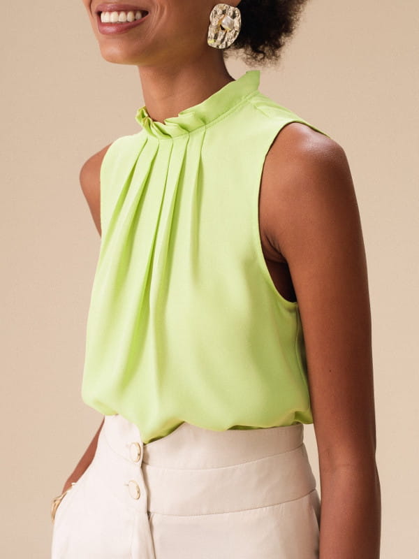 Modelos de blusas femininas: modelo vestindo uma blusa de crepe básica com pregas cor lima.