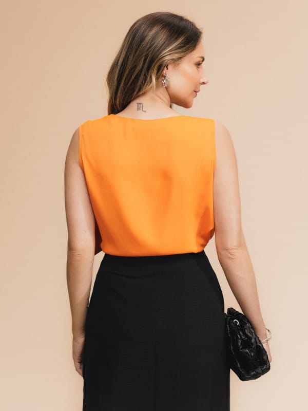 Blusa feminina de crepe: modelo vestindo uma blusa feminina de crepe com faixa laranja no ombro - costas.