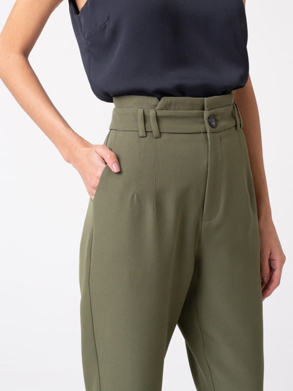 Calça alfaiataria feminina: modelo vestindo uma calça feminina alfaiataria com elastano e passantes duplos verde - detalhes.