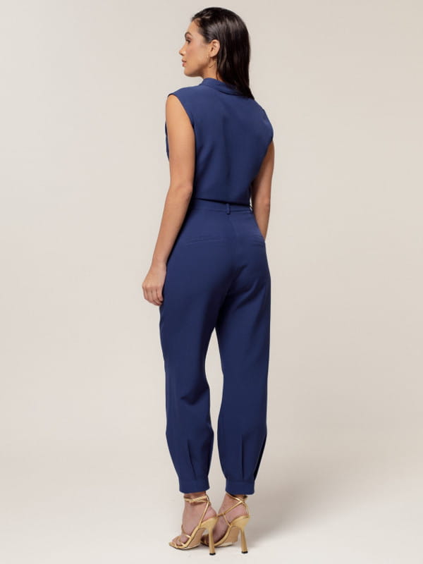 Calça alfaiataria feminina: modelo vestindo uma calça alfaiataria feminina com modelagem cenoura - costas.