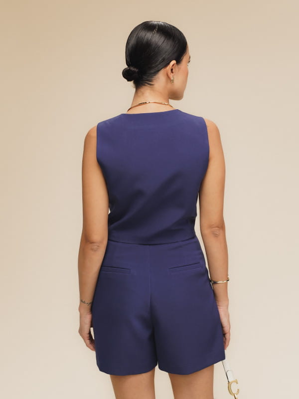 Colete alfaiataria feminino: modelo vestindo um colete feminino twill mini azul - costas.