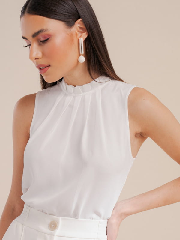 Como combinar cores de roupas: modelo vestindo uma blusa de crepe básica com pregas off white.
