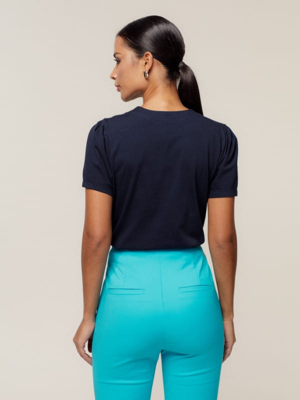 Cores que combinam com azul: modelo vestindo uma blusa feminina de malha decote V e manga com franzido azul marinho - costas.