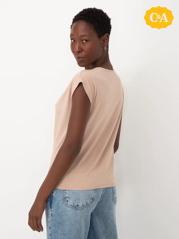 Cores que combinam com bege: modelo vestindo uma blusa feminina gola degagê manga curta areia - costas.