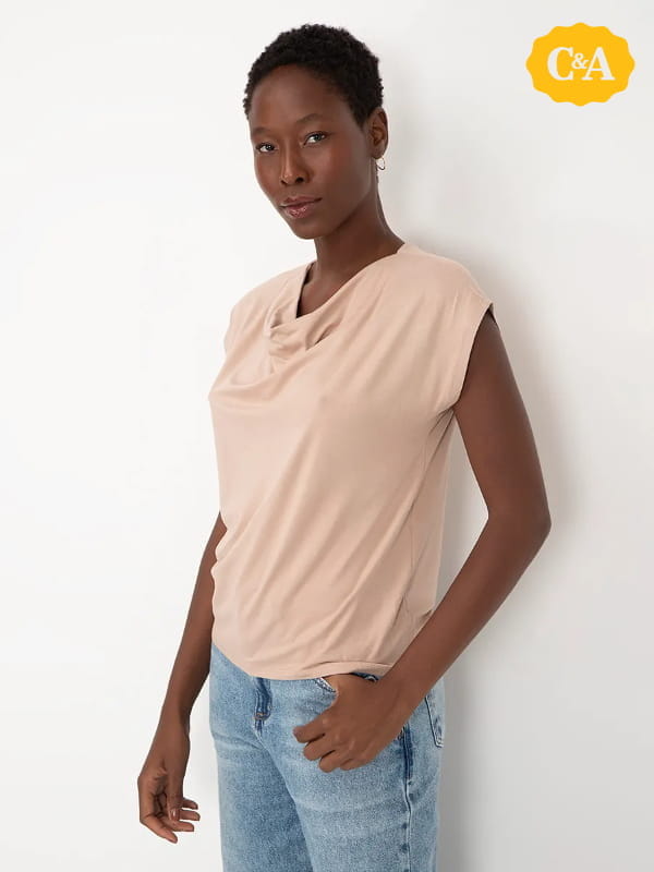 Cores que combinam com bege: modelo vestindo uma blusa feminina gola degagê manga curta areia.
