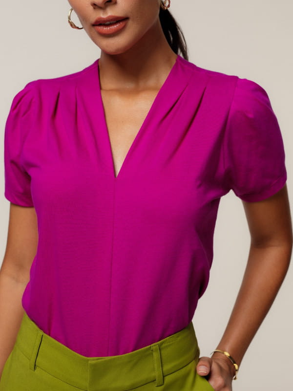 Cores que combinam com fucsia: modelo vestindo uma blusa de malha decote V - detalhes.
