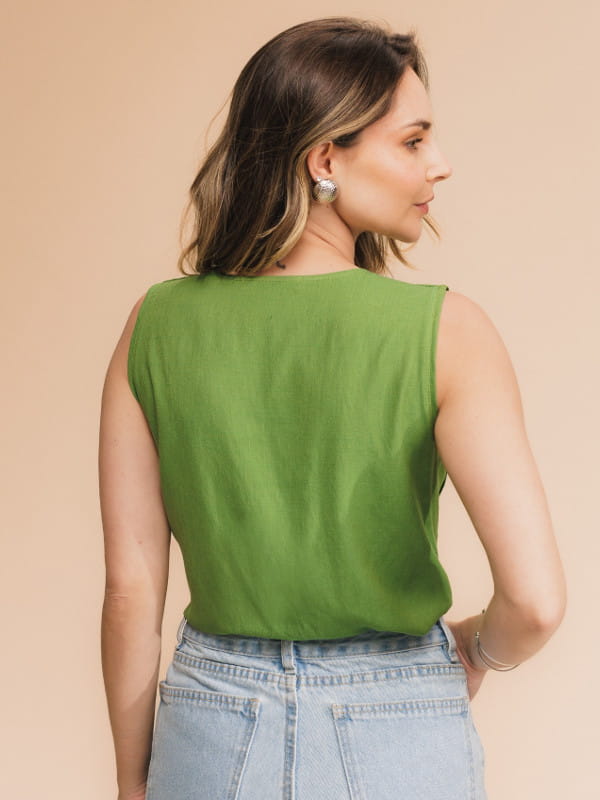 Cores que combinam com verde: modelo vestindo uma regata com decote V na cor verde com uma saia jeans - costas.