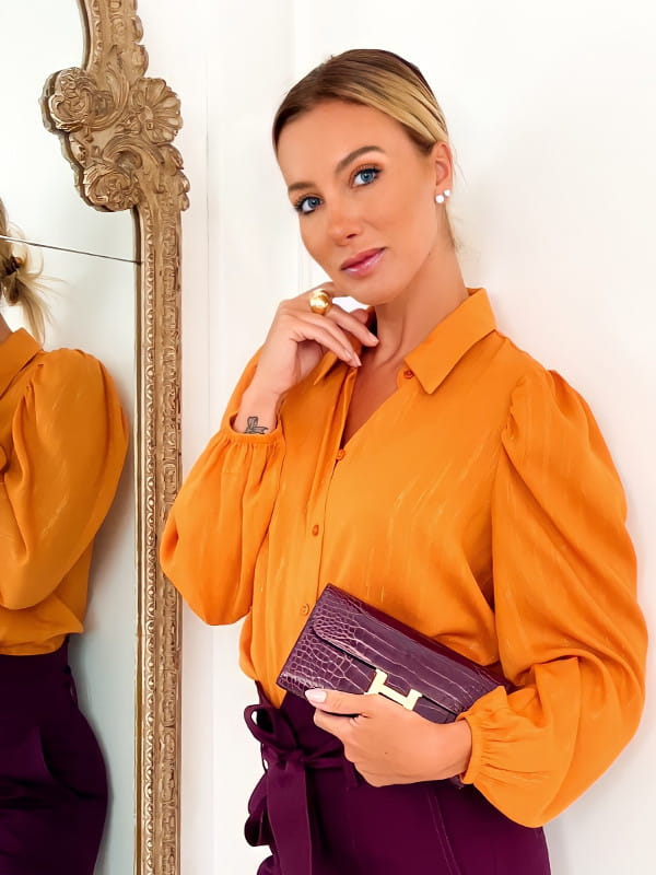 Estilos de roupas femininas: modelo com uma camisa de chiffon com manga bufante laranja.