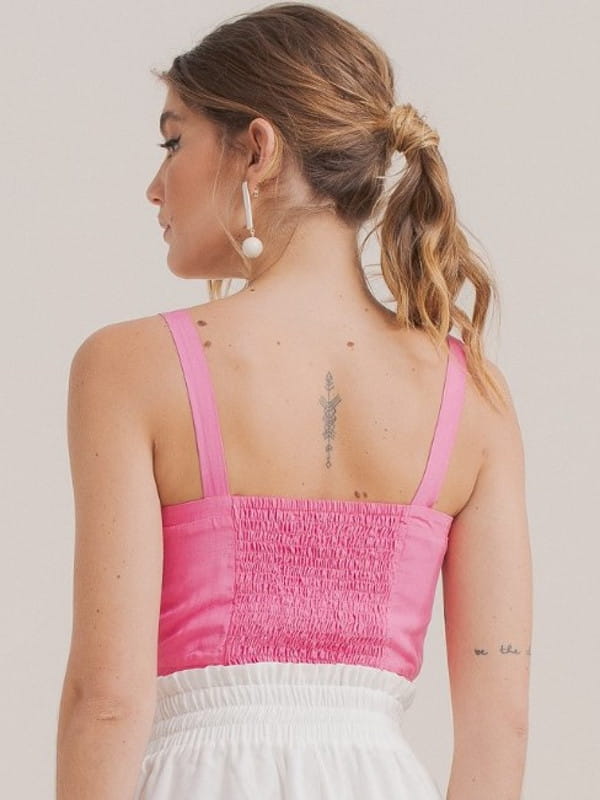 Looks com as costas a mostra: modelo com uma blusa cropped rosa - costas.