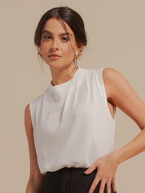 Moda e estilo: o que as cores transmitem: modelo vestindo uma blusa de crepe com pregas no ombro branca com calça preta.