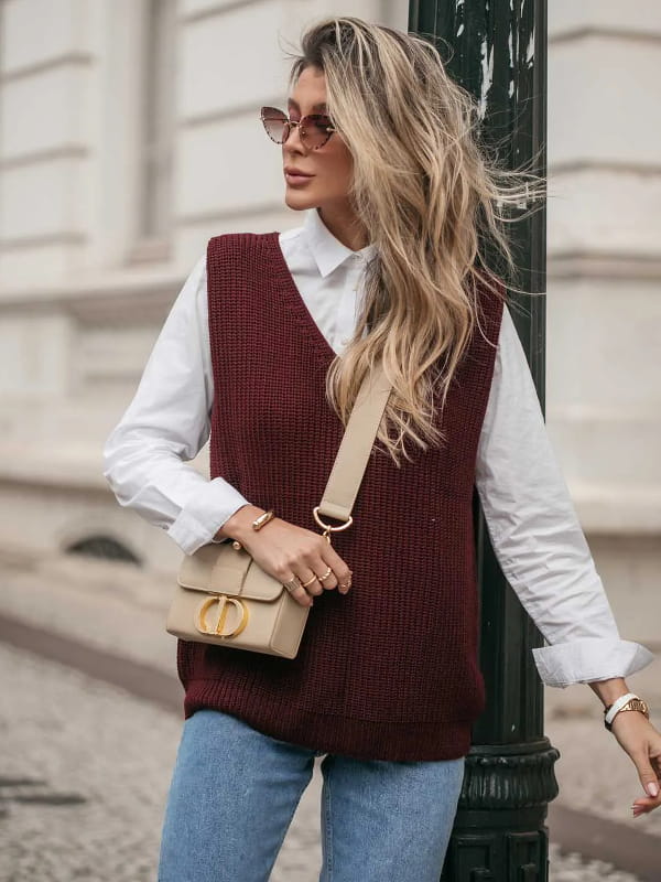 Moda Outono Inverno 2022: modelo vestindo um colete de tricot marsala e calça jeans.