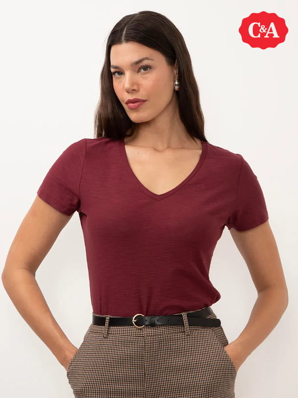 Modelos de blusas femininas: modelo vestindo uma blusa básica flamê manga curta decote V vinho.