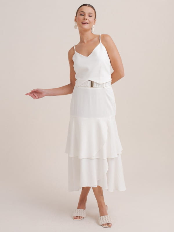 Peças e tendências que rendem looks para ficar elegante: modelo com uma saia midi off white.