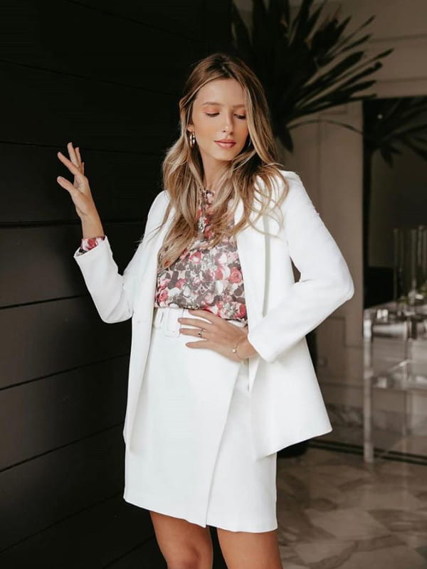 Peças fundamentais no guarda-roupa feminino: modelo com um blazer e saia brancos.