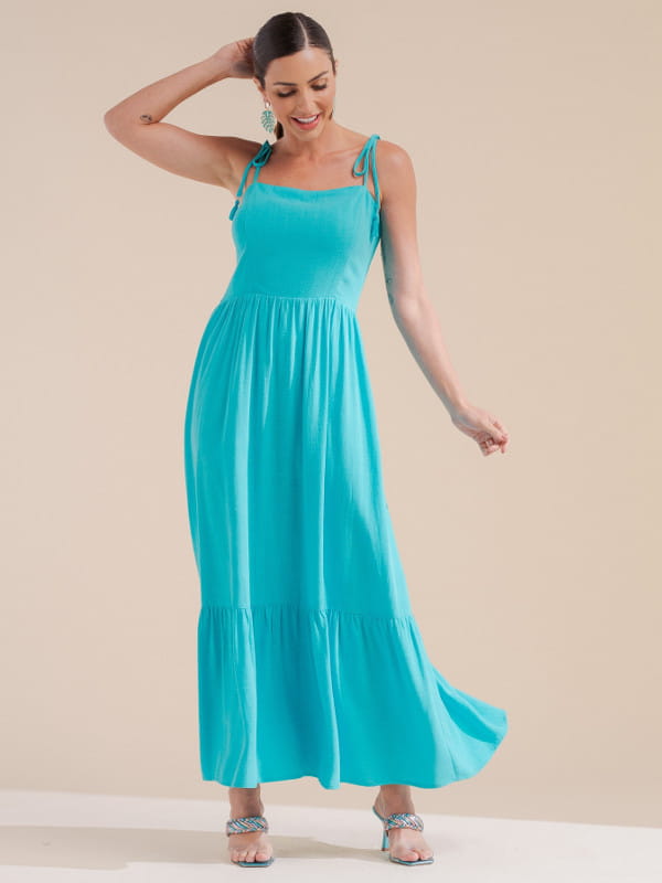 Peças que estão sempre em alta no verão: modelo com um vestido midi azul.