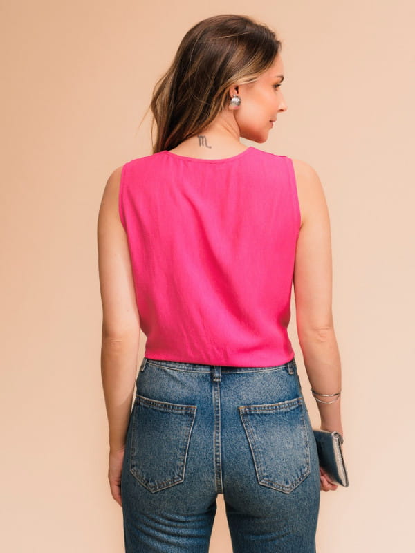 Qual será a cor do verão 2024: modelo vestindo uma regata com decote V na cor pink com uma calça jeans - costas.