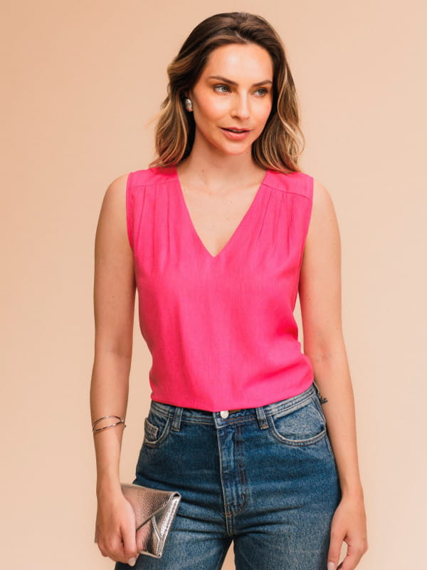 Qual será a cor do verão 2024: modelo vestindo uma regata com decote V na cor pink com uma calça jeans.