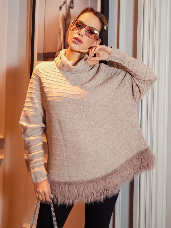 Moda Outono Inverno 2022: modelo vestindo um poncho de tricot com plumas na barra.