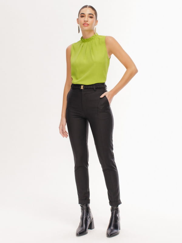 Truques para mulheres altas: modelo com uma blusa verde e calça preta e bota.